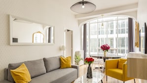 A modern living room with a grey sofa, yellow cushions, a marble coffee table, and a yellow armchair. - Merveil - Family Suite - Louvre - Sentier II (Paris)