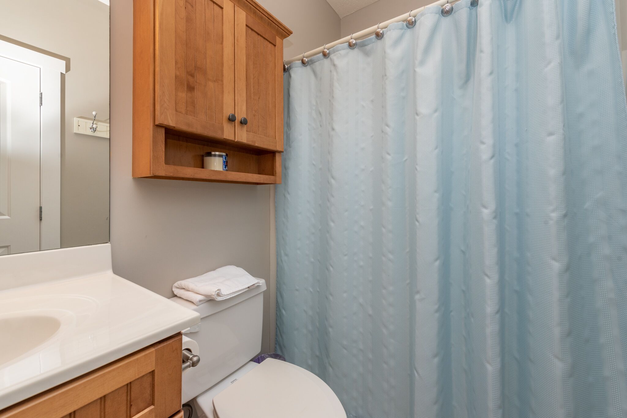 Een badkamer met een wit wastafel, houten kast en een blauw douchegordijn.