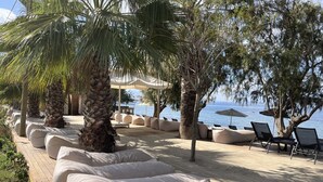 Un espace de détente aménagé sur la plage, avec des sièges confortables et des parasols, offrant une vue sur la mer.