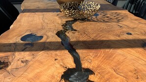 Une table en bois ornée d’un vase de fleurs et d’un bol décoratif.