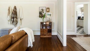 A living room with a brown leather sofa, a wooden cabinet with glass doors, and a checkered floor.