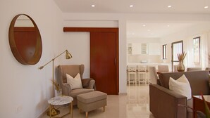 Uma sala de estar moderna com sofá, puf e mesa lateral com abajur.