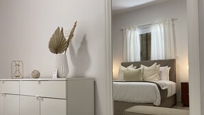 Quarto moderno com cama, mesa de cabeceira e espelho refletindo o ambiente.