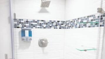 A shower with a glass door, a tiled floor, and a showerhead.