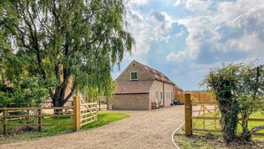 A gravel driveway leading to a brick building with a sloped roof. - The Hayloft at Warren House (Market Rasen)