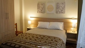 A hotel room with a bed, two bedside lamps, a wooden headboard, and wall art. - Ruinas: Spacious 2-bedroom apartment in San Blas market area. Big kitchen! (Cusco)