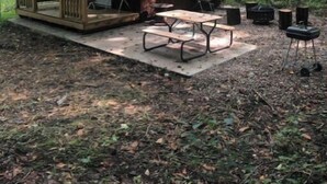 A small wooden cabin with a porch, a picnic table, and outdoor seating.
