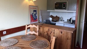 A wooden dining table with woven placemats, a microwave, and a coffee maker in a kitchen with wooden cabinets and a white countertop. - 100m from resort center, 8th floor, balcony, tv, 30m², Les Arcs (Les Arcs)
