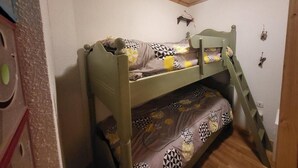 Een stapelbed met een ladder, een klein plankje en een lamp bevestigd aan de muur.