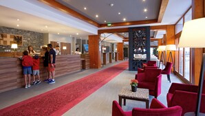 Eine Hotelhalle mit einer Rezeption, einem roten Teppich und roten Stühlen.