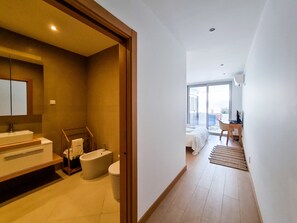 A modern hotel room with a bathroom, a balcony, and a desk with a chair. - FLH Lagos Central Flat with Terrace (Lagos)