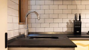 A kitchen with a stainless steel sink, a wooden cabinet, and a knife block on the countertop. - Amplio departamento en el Corazon de Colinia Roma (Ciudad de México)