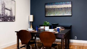 A dining area with a dark blue accent wall, a framed cityscape painting, and a modern table set with chairs. - Amplio departamento en el Corazon de Colinia Roma (Ciudad de México)