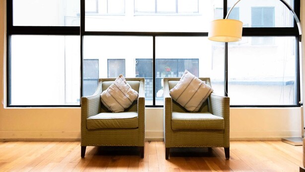 Two armchairs with cushions facing a large window with a view of buildings. - Amplio departamento en el Corazon de Colinia Roma (Ciudad de México)