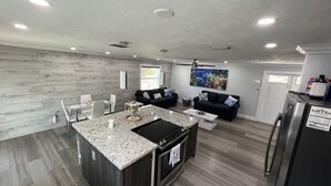 Une cuisine moderne dotée de plans de travail en granit, d’un four encastré et d’un coin repas avec une table et des chaises en verre.