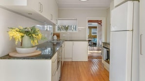 A modern kitchen with white cabinetry, a wooden floor, and a vase of yellow flowers on the counter. - Collwood Cottage. Four Beds + Fireplace. Orange. (Orange)