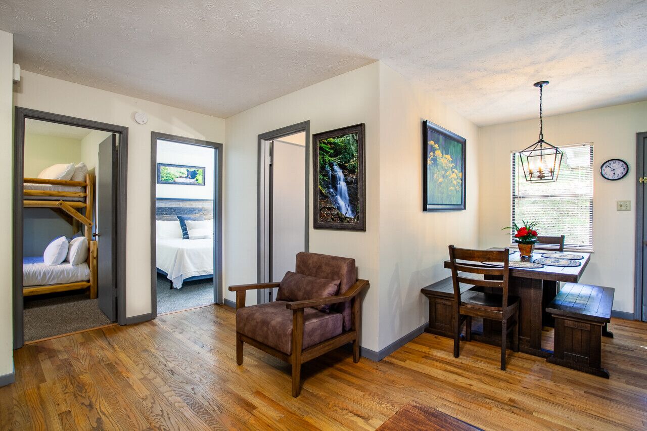 Une chambre avec un lit superposé, un coin repas avec une table et des chaises, et un fauteuil.