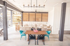 Une pièce spacieuse avec une table à manger en bois entourée de chaises, un ventilateur de plafond et une rangée de stores en bois.