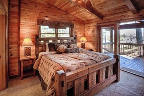 A wooden cabin bedroom with a bed, two bedside lamps, a window, and a balcony.
