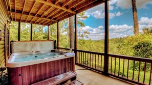 Un bain à remous sur une terrasse en bois, avec vue sur un paysage boisé.