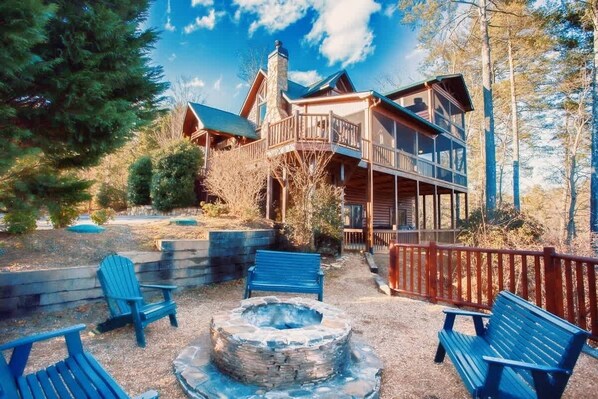 A lodge with a stone fire pit, outdoor seating, and a wooden deck.