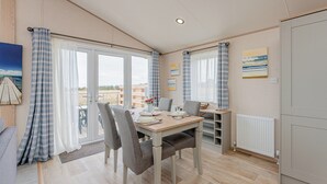 Ein Essbereich mit einem Tisch für vier Personen, einem Heizkörper und Blick ins Freie durch große Fenster.