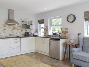 A modern kitchen with white cabinets, a stainless steel refrigerator, and a window with a view of greenery. - 2 bedroom accommodation in Stackpole (Stackpole)