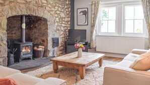 A living room with a stone fireplace, a television, a wooden coffee table, and a sofa.