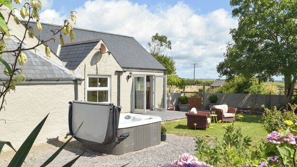 A house with a hot tub, a patio with outdoor furniture, and a garden with flowers.