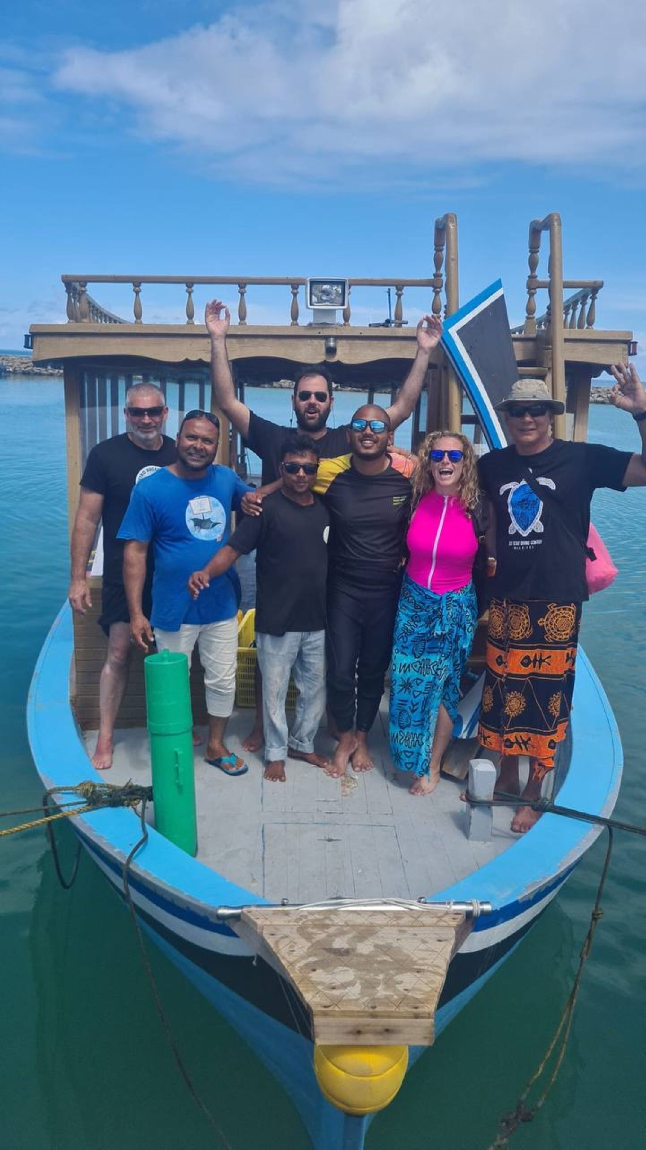 A group of people on a small boat with a wooden structure in the background.