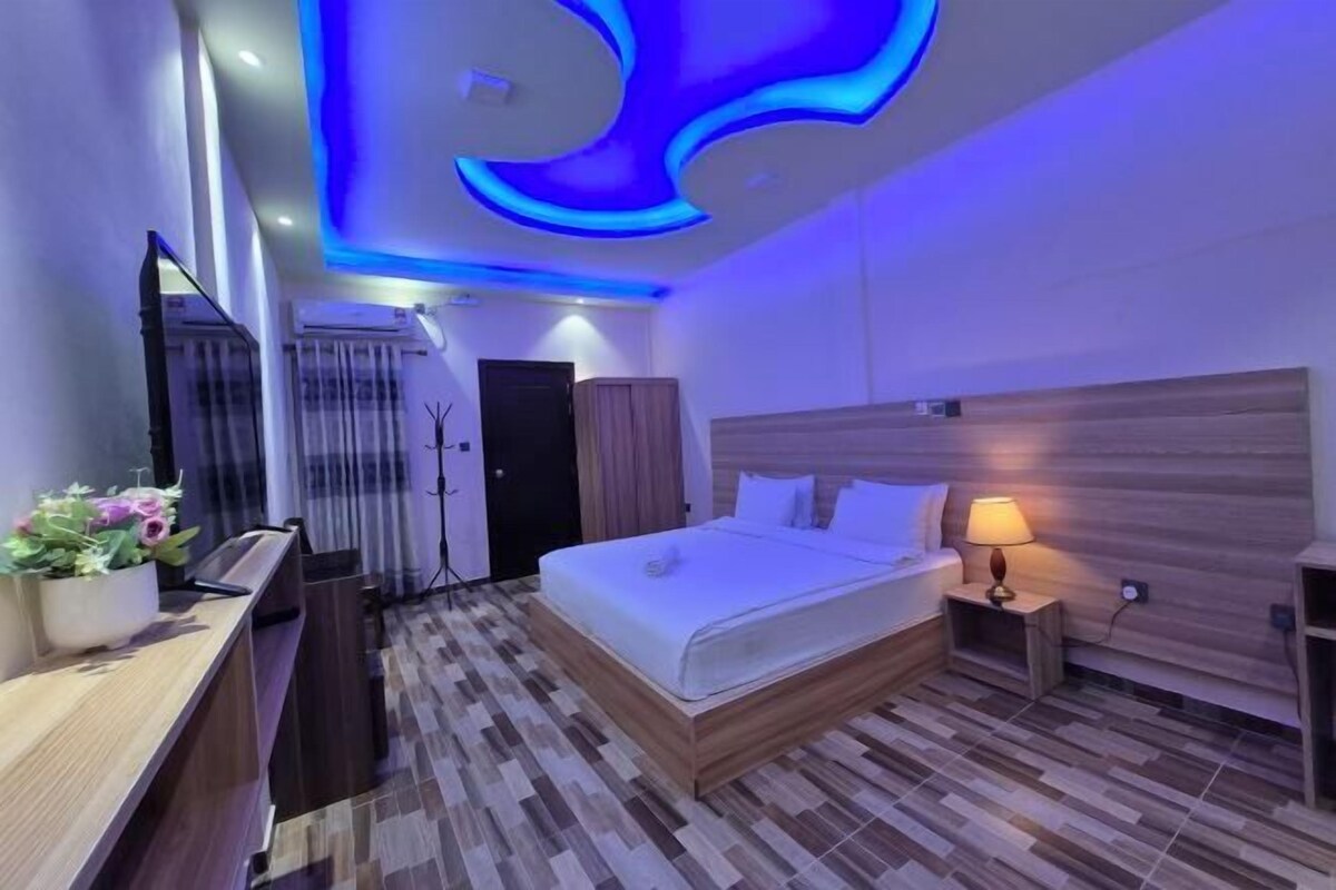 Une chambre d’hôtel moderne équipée d’un lit, d’une table de chevet, d’une lampe et d’un luminaire décoratif au plafond.
