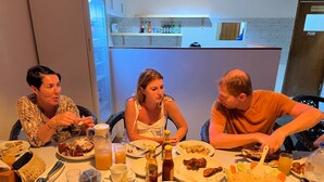 Un grupo de personas comiendo en una mesa con diferentes platos, bebidas y un teléfono móvil.