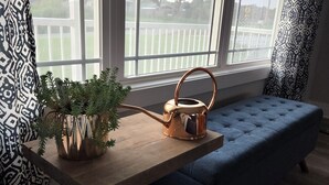 Un rincón acogedor con una mesa de madera, un banco tapizado en azul y un otomán blanco mullido.