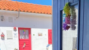 A building with a red door, a white wall with a 'Peace and Love' sign, and a blue door with a wreath. - Casal DOS Carpinteiros 4 (Silveira)