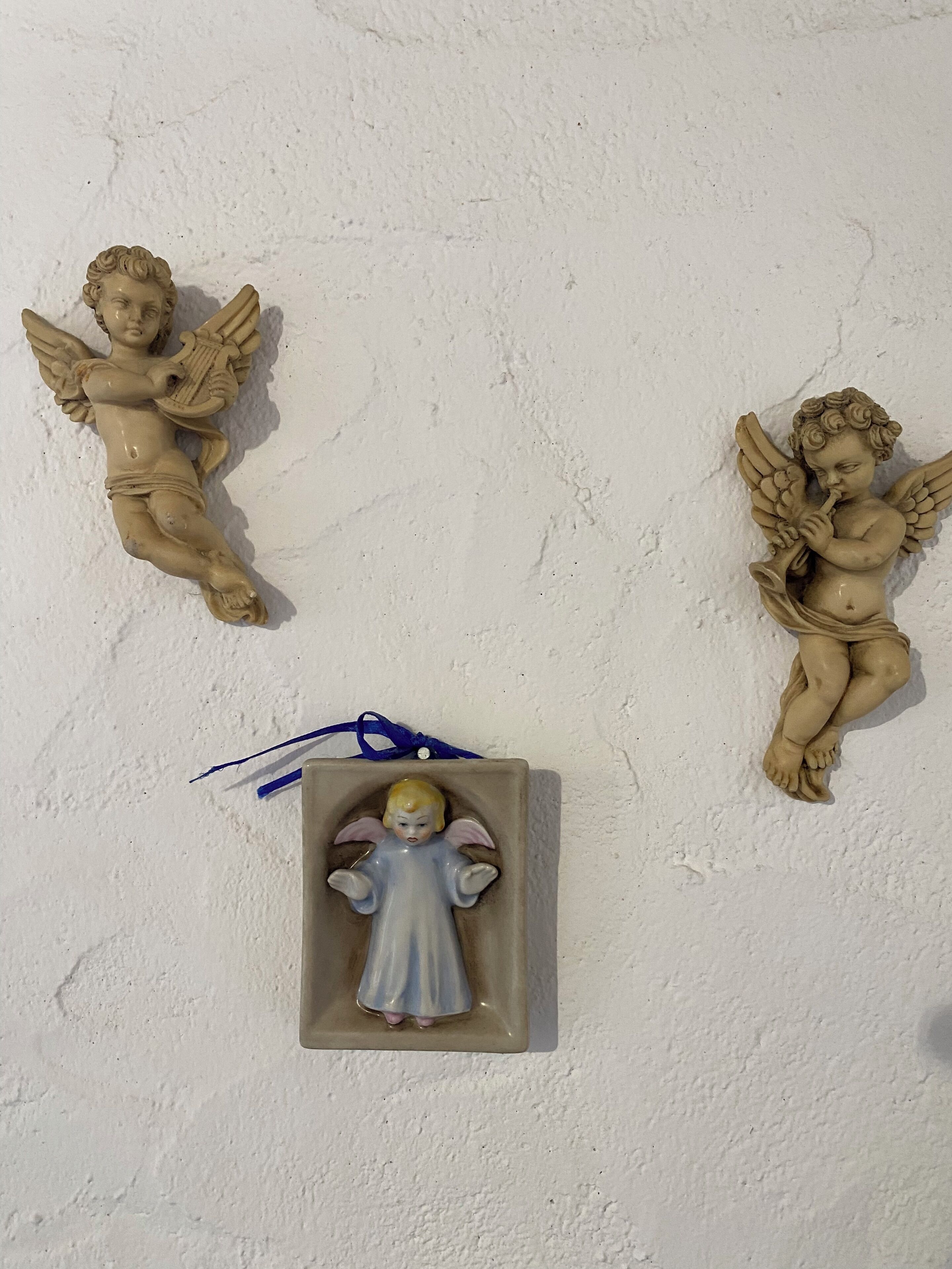 Tre änglafigurer på en vägg med en intressant yta.