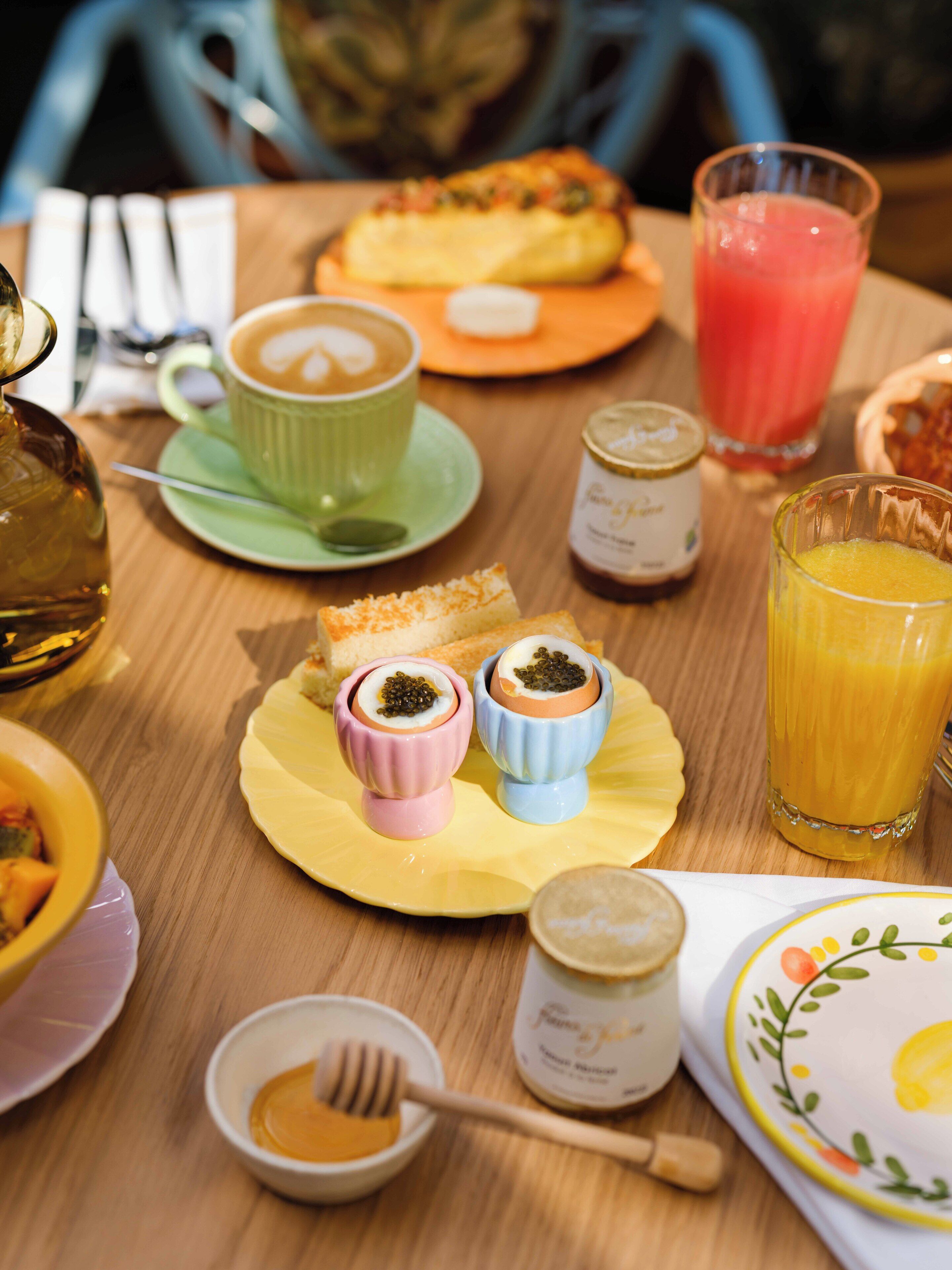 A breakfast table with various food items, including bread, a cup of coffee, a glass of orange juice, and small bowls with condiments.