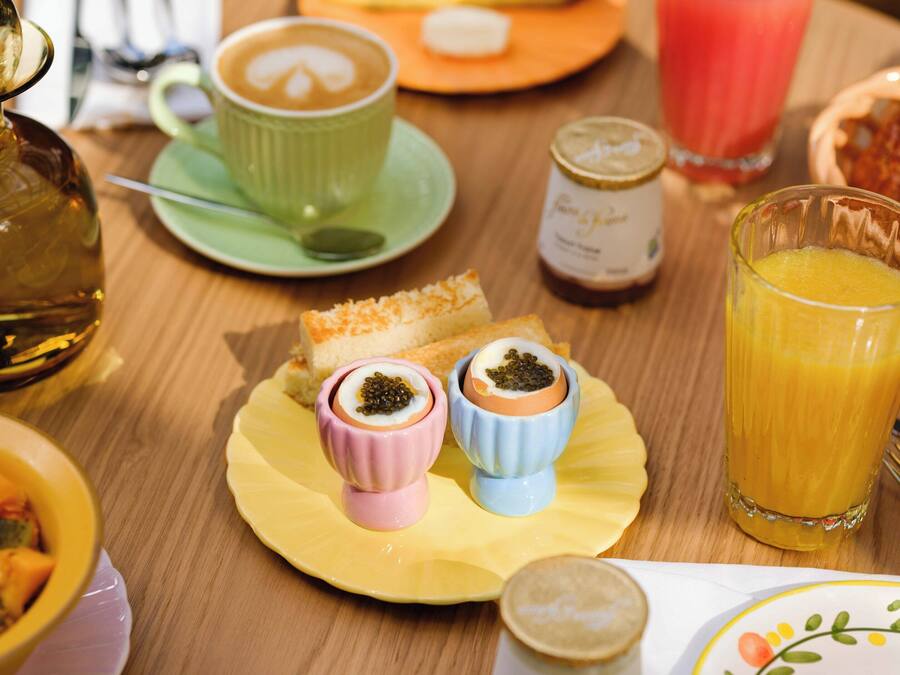A breakfast table with various food items, including bread, a cup of coffee, a glass of orange juice, and small bowls with condiments.