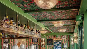 A bar area with a long counter, multiple bar stools, and a ceiling with floral patterns. - La Fantaisie (Paris)