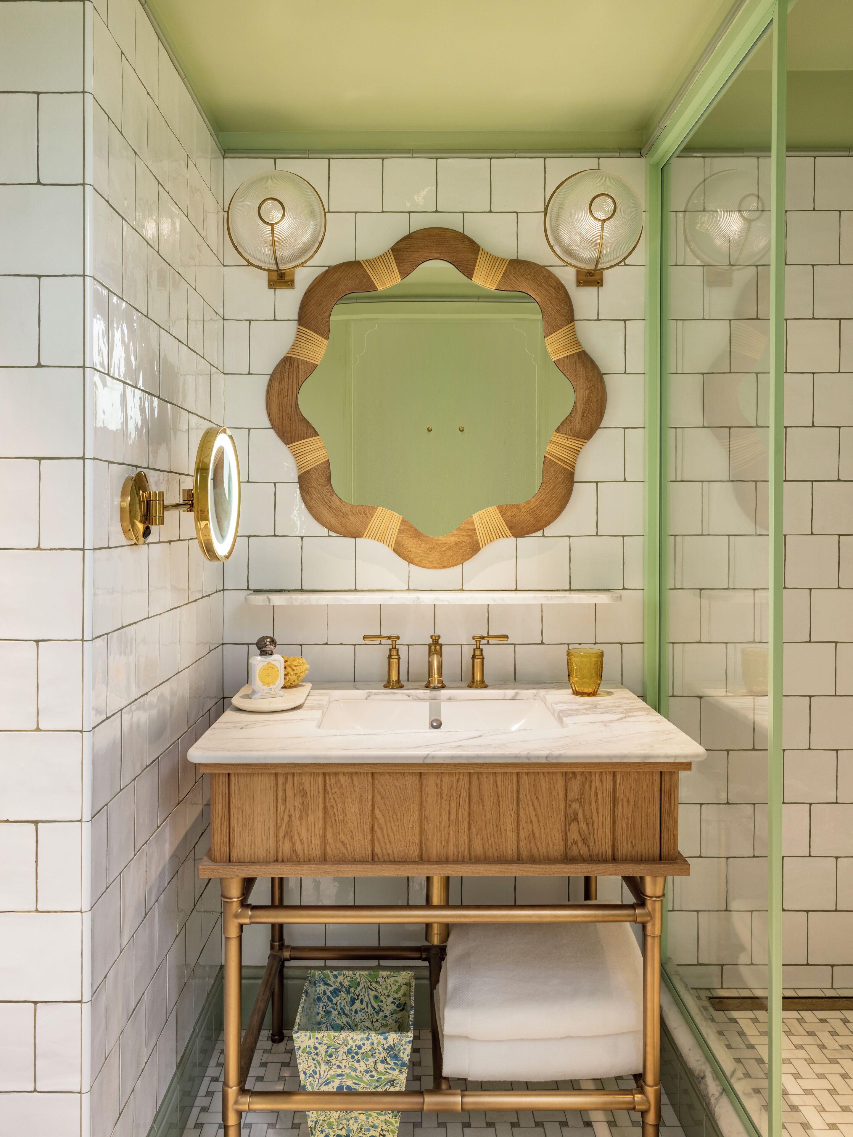 A bathroom with a wooden vanity, a mirror with a decorative frame, two wall-mounted fans, and a tiled backsplash.