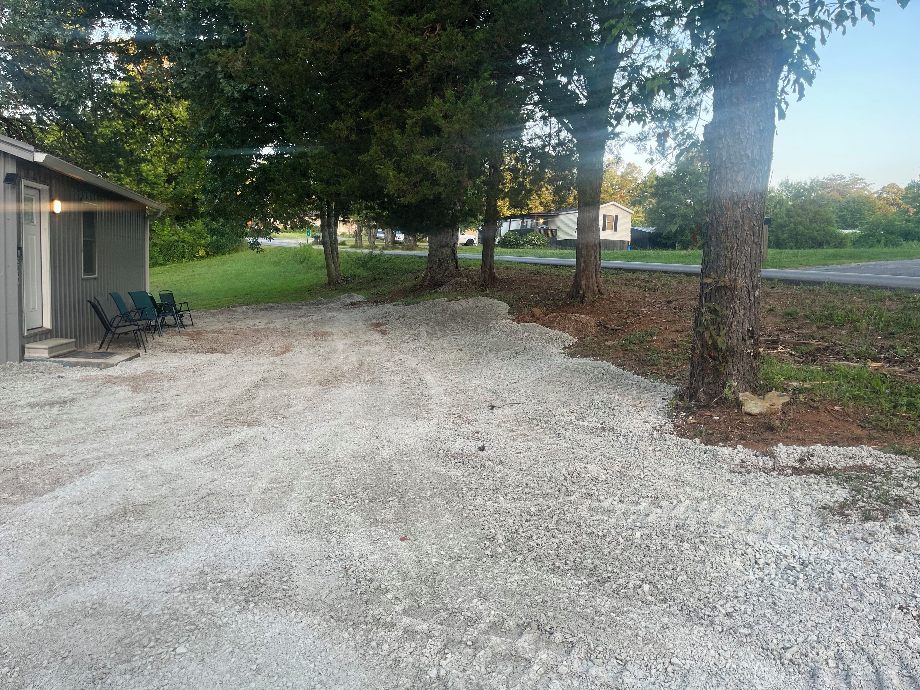 Un camino de grava conduce a un edificio con un porche pequeño y mobiliario exterior.