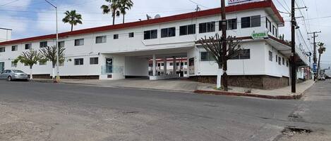 A white building with a red roof, a sign reading "ALBERCA", and a covered entrance.