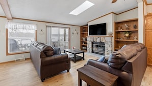 Un salon avec une cheminée, un téléviseur et un ventilateur de plafond.