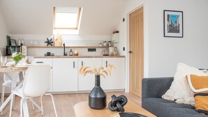 Una cucina moderna con mobili bianchi, un piano di lavoro in legno e un lucernario.