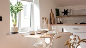 Una cucina moderna con un tavolo da pranzo rotondo, sedie bianche, una pianta in vaso e una decorazione a stella sul muro.