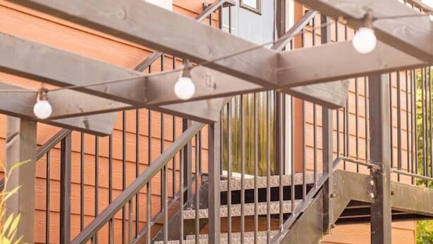 Una scala in legno con ringhiera in metallo che conduce a un edificio con un cartello che riporta la scritta “THE STUDIO”.
