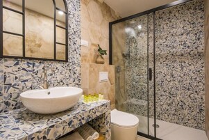 A bathroom with a large sink, a mirror, a toilet, and a shower enclosure.