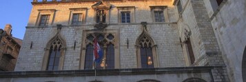 A historic building with arched windows and a flagpole.