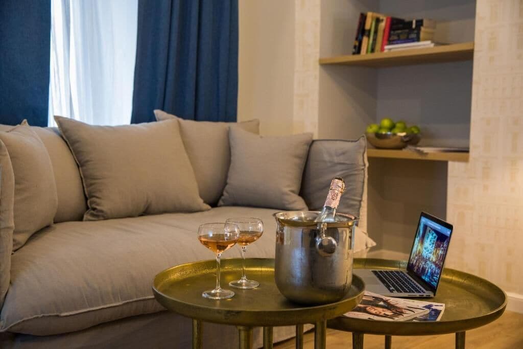 Ett vardagsrum med en soffa, ett litet bord med en bärbar dator och ett glas, samt en bokhylla i bakgrunden.