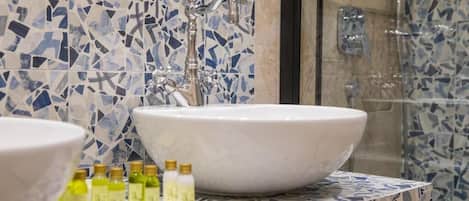 A bathroom with a large white sink, a mirror, and a shower area.