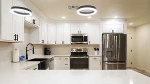 A modern kitchen with white cabinets, stainless steel appliances, and a marble countertop. - Cozy house w/ putting green, mtn. views, BBQ (Fountain Hills)